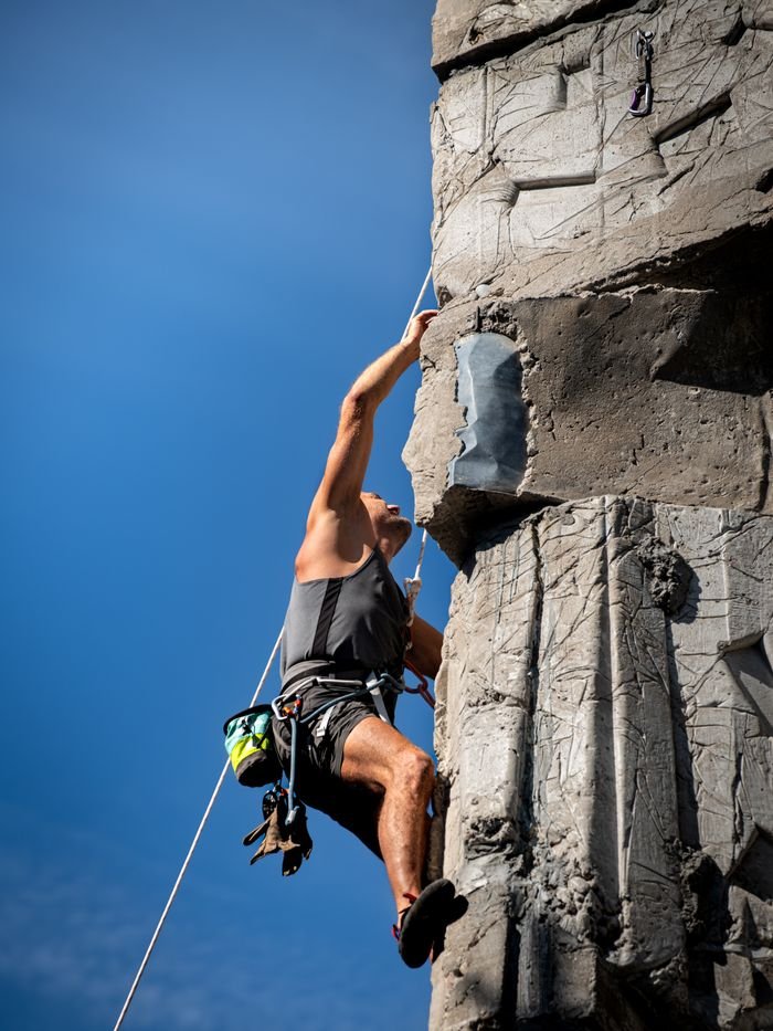 Rock climber with gear scaling artificial wall outdoors in Kaunas, Lithuania.